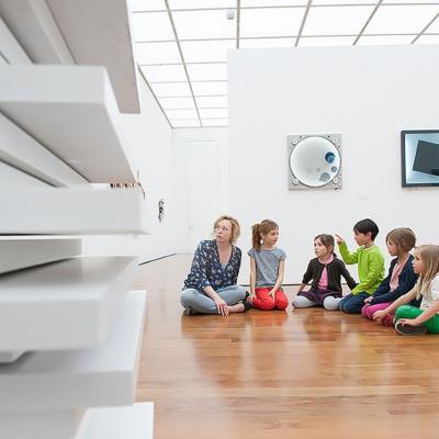 Kinder sitzen im Museum auf Holzfußboden