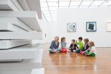 Kinder sitzen im Museum auf Holzfußboden